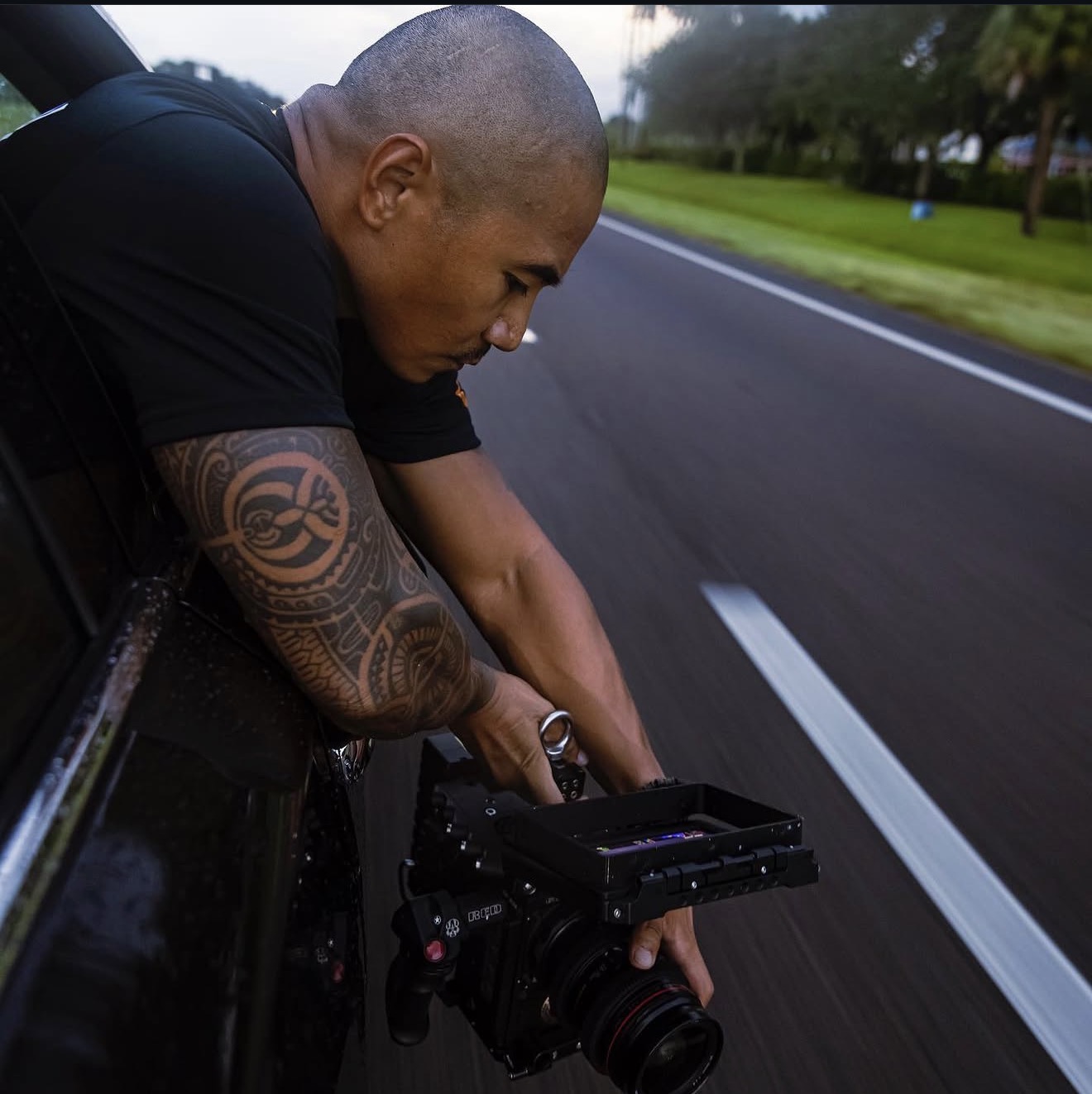 Director of photography operating cinema camera from vehicle